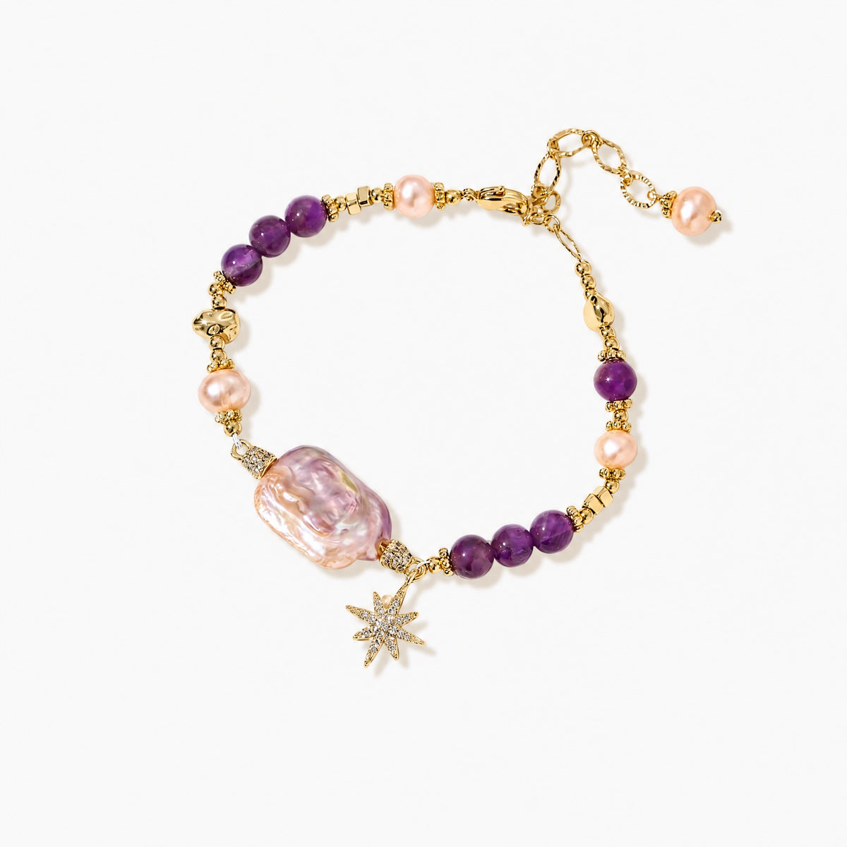 Gold-plated bracelet with baroque pearl centerpiece, amethyst beads, and crystal star charm on white background.