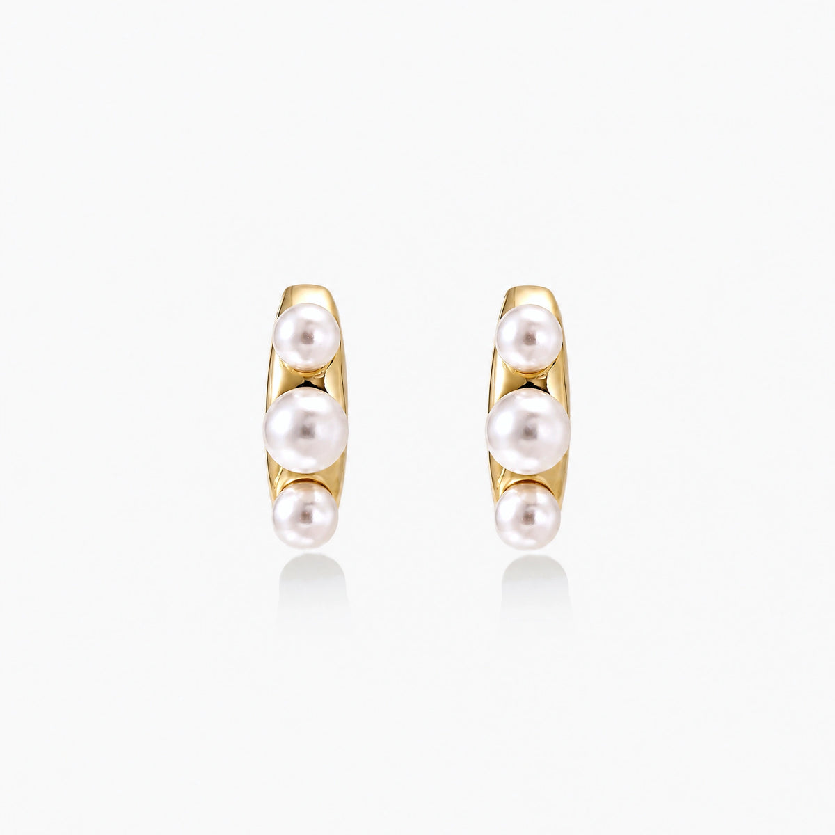 14K gold-plated curved stud earrings with three white freshwater pearls aligned vertically on cream background