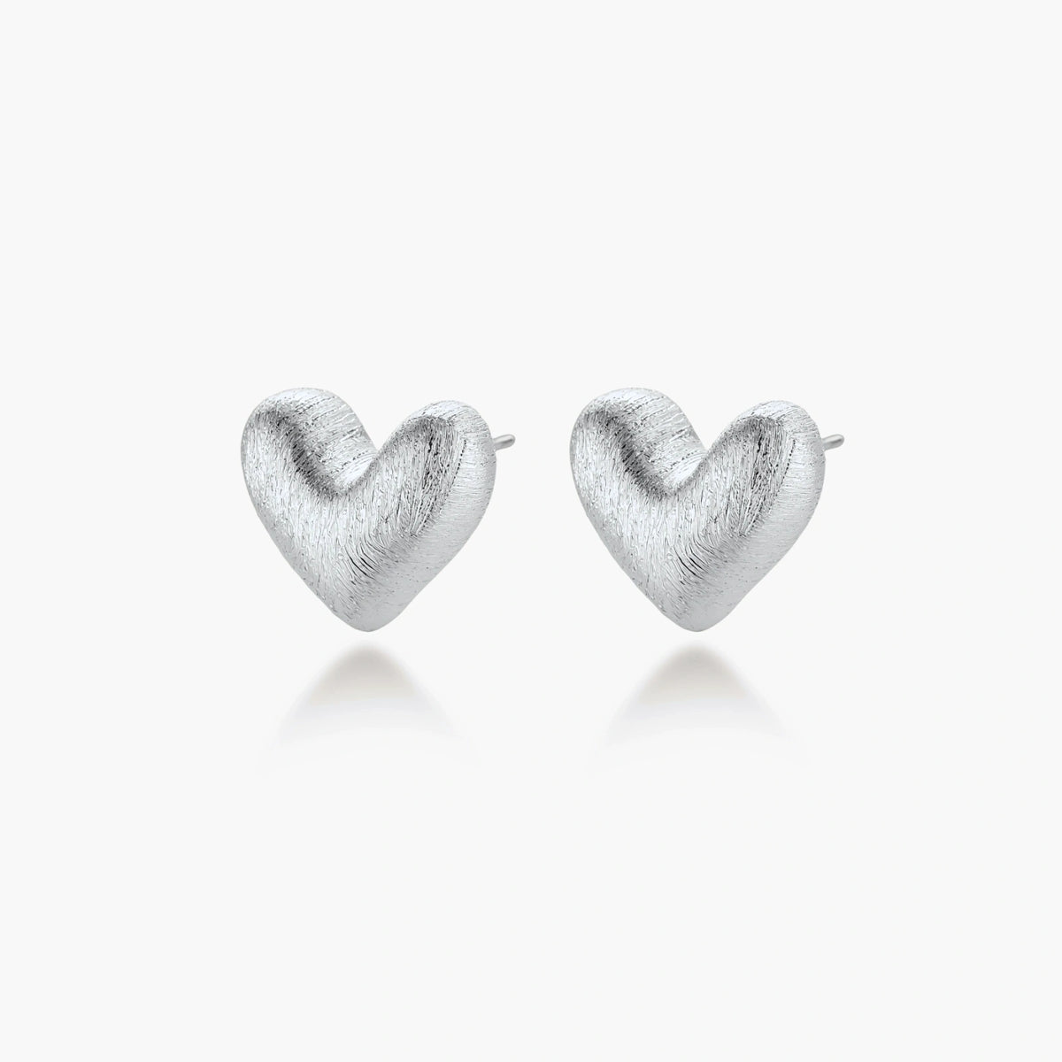Pair of brushed platinum-plated 925 sterling silver puffy heart stud earrings on a cream background.