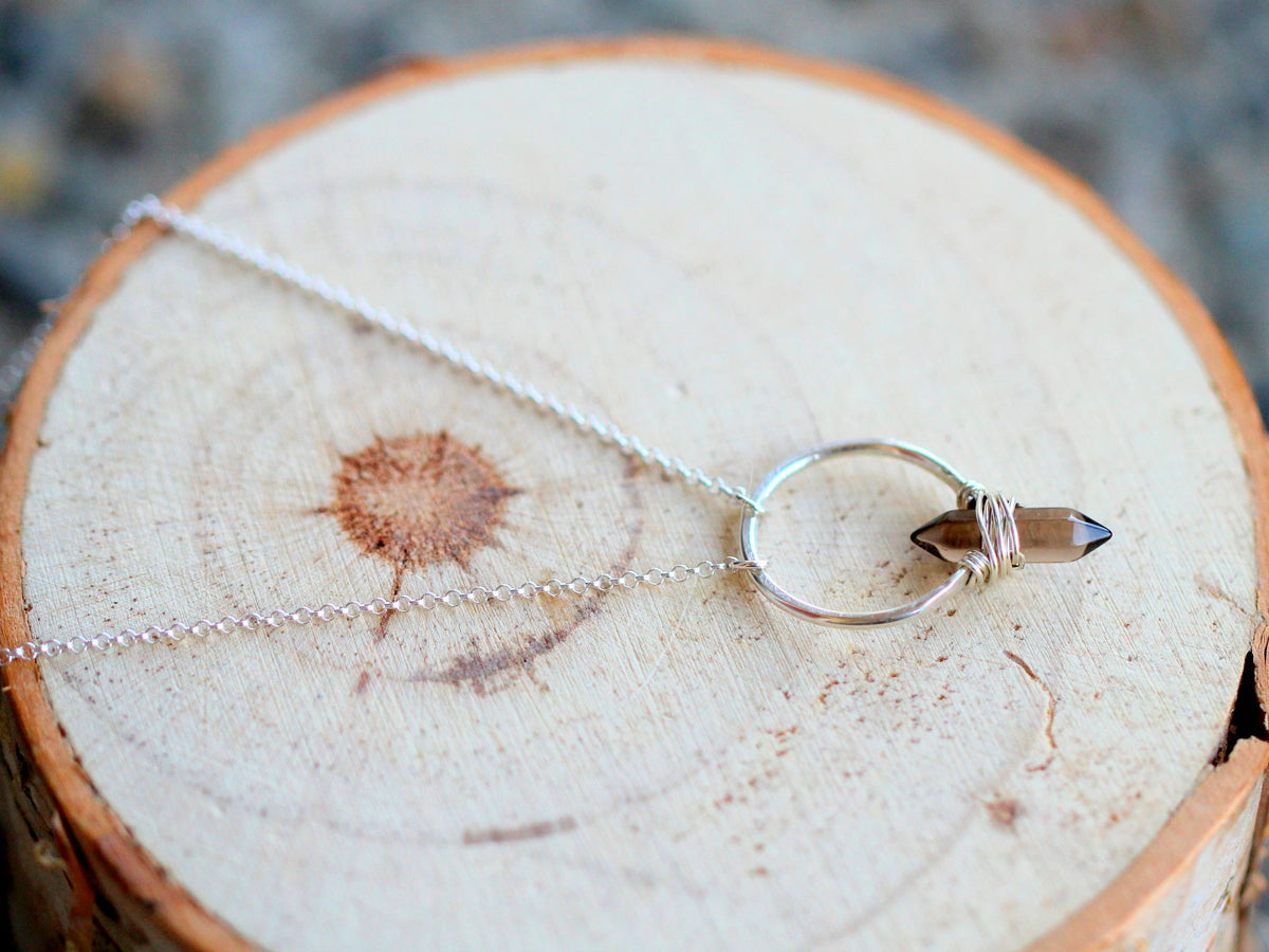 Smoky quartz crest necklace laid flat with silver chain and crest charm
