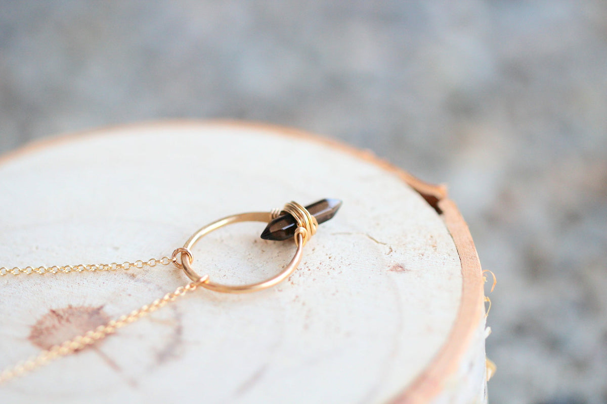 Smoky quartz crest necklace on neutral background, showing stone and chain