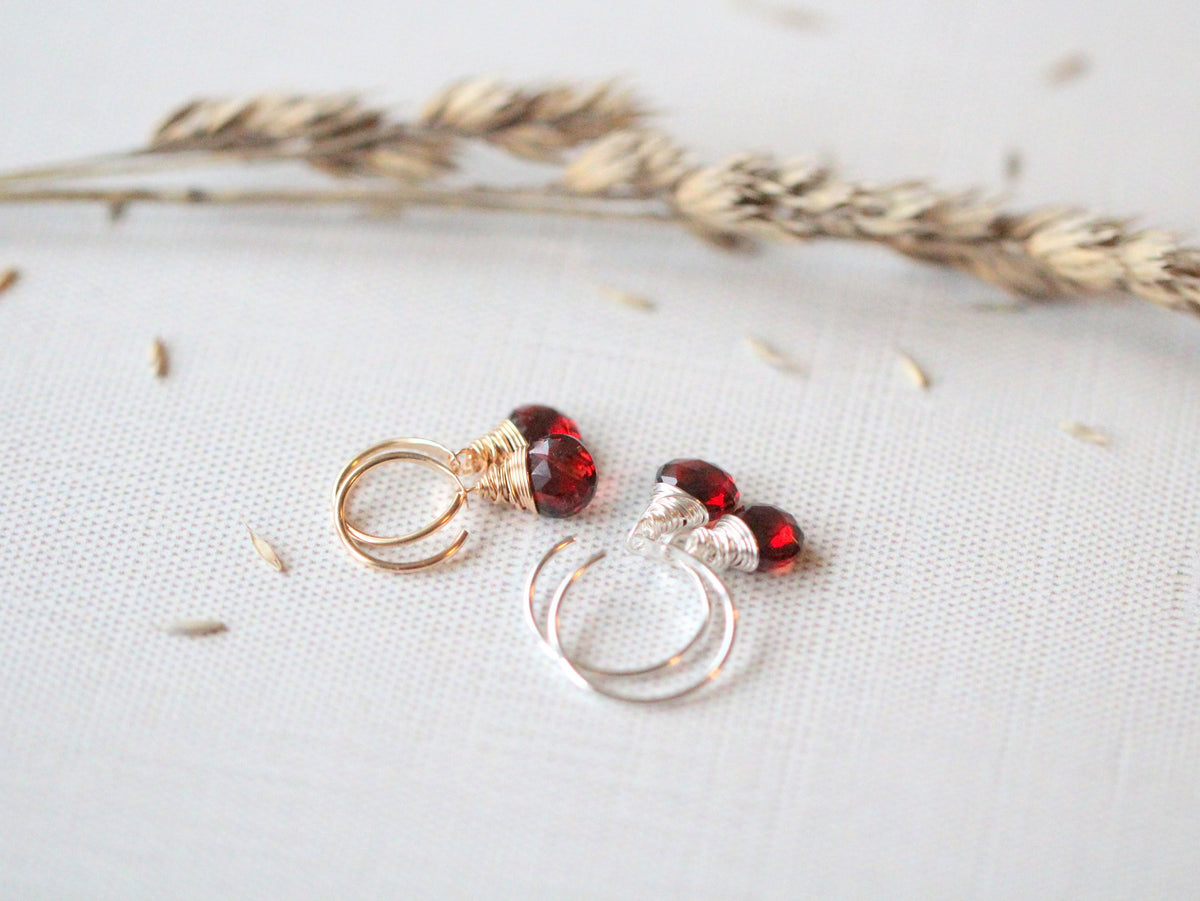 Garnet dangle hug earrings detail, gold hoop with a dangling garnet stone for a subtle pop of color