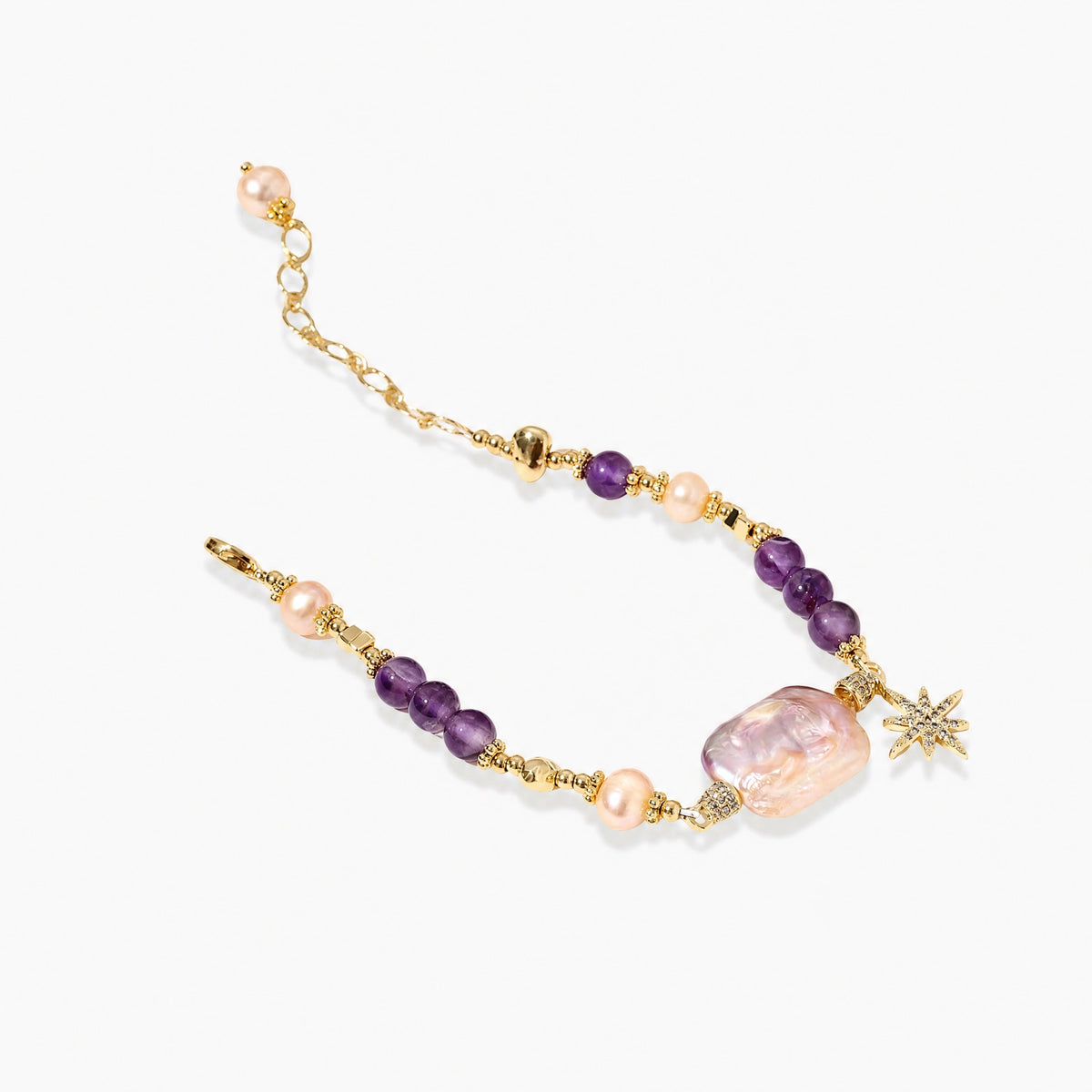 Gold-plated bracelet with baroque pearl centerpiece, amethyst beads, and crystal star charm on white background.