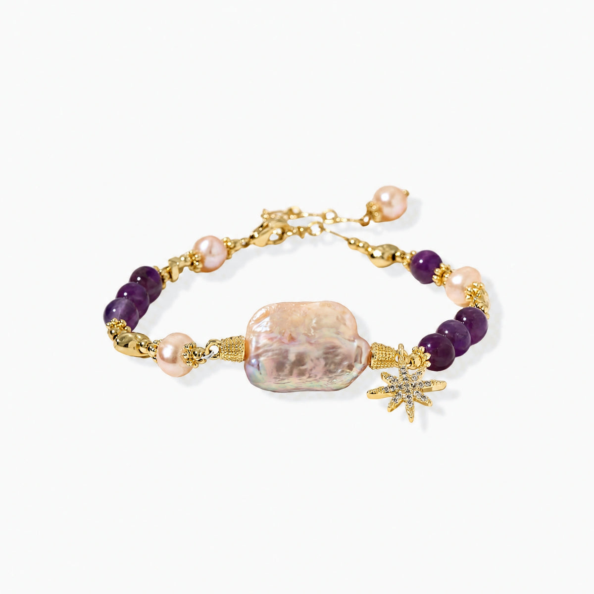 Gold-plated bracelet with baroque pearl centerpiece, amethyst beads, and crystal star charm on white background.