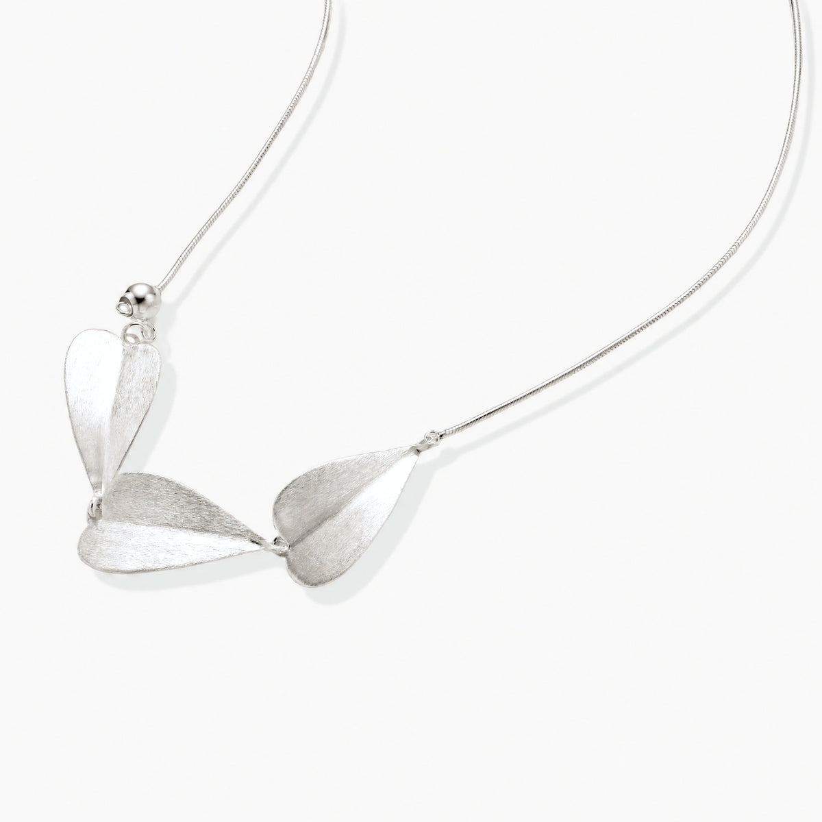 Minimalist sterling silver necklace with three brushed leaf-shaped pendants on delicate chain against white background