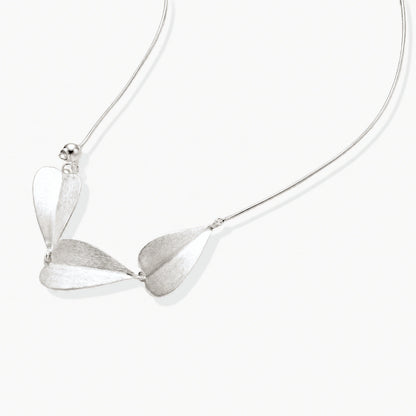 Minimalist sterling silver necklace with three brushed leaf-shaped pendants on delicate chain against white background