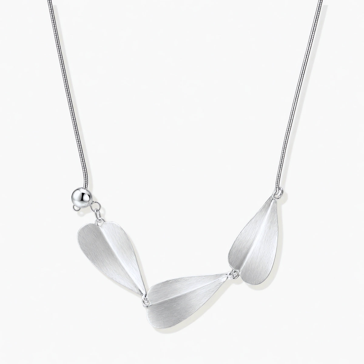 Minimalist sterling silver necklace with three brushed leaf-shaped pendants on delicate chain against white background