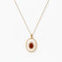Gold plated eco-brass necklace with an oval white pendant, a central red-brown stone and a zirconia halo on a cream background.