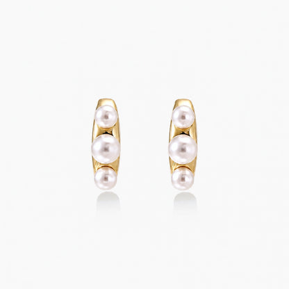 14K gold-plated curved stud earrings with three white freshwater pearls aligned vertically on cream background