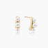 14K gold-plated curved stud earrings with three white freshwater pearls aligned vertically on cream background