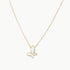 Gold-plated butterfly pendant with iridescent mother of pearl inlay on delicate chain against cream background.
