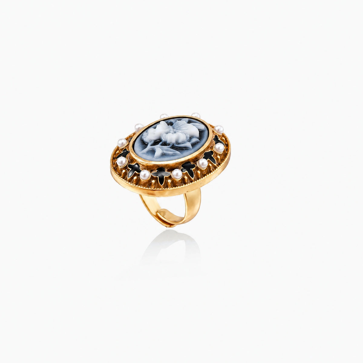 Gold-plated ring with oval blue floral cameo, pearl accents, and black enamel detailing on white background.