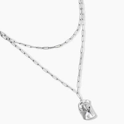 Modern textured hoop earrings and layered chain necklace with liquid metal pendant in silver and gold finishes.