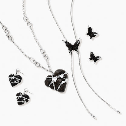 Dark wood butterfly earrings and necklace with silver chain accents on white background, showing natural grain texture.