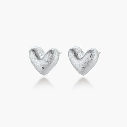 Pair of brushed platinum-plated 925 sterling silver puffy heart stud earrings on a cream background.