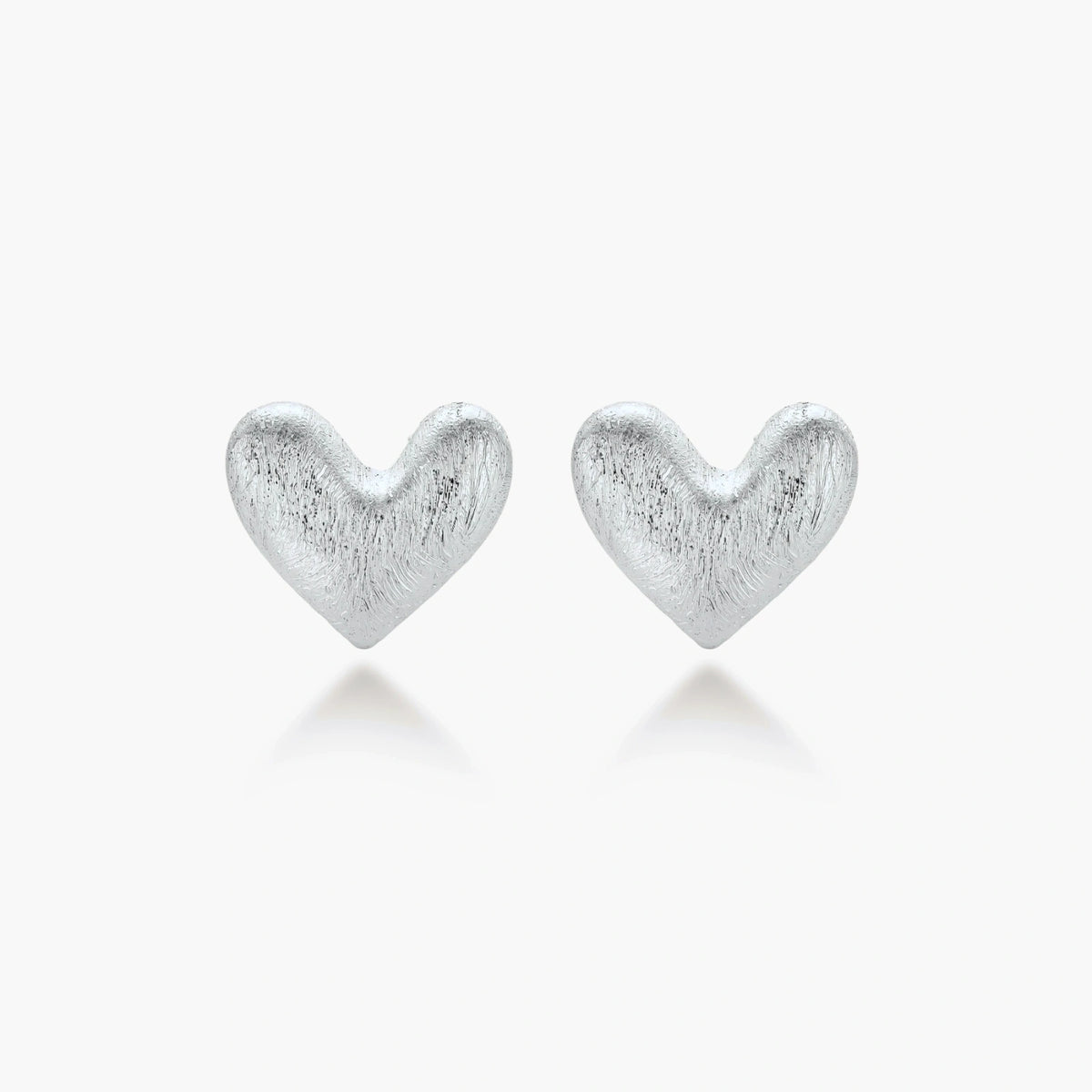 Pair of brushed platinum-plated 925 sterling silver puffy heart stud earrings on a cream background.