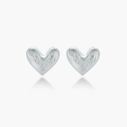 Pair of brushed platinum-plated 925 sterling silver puffy heart stud earrings on a cream background.