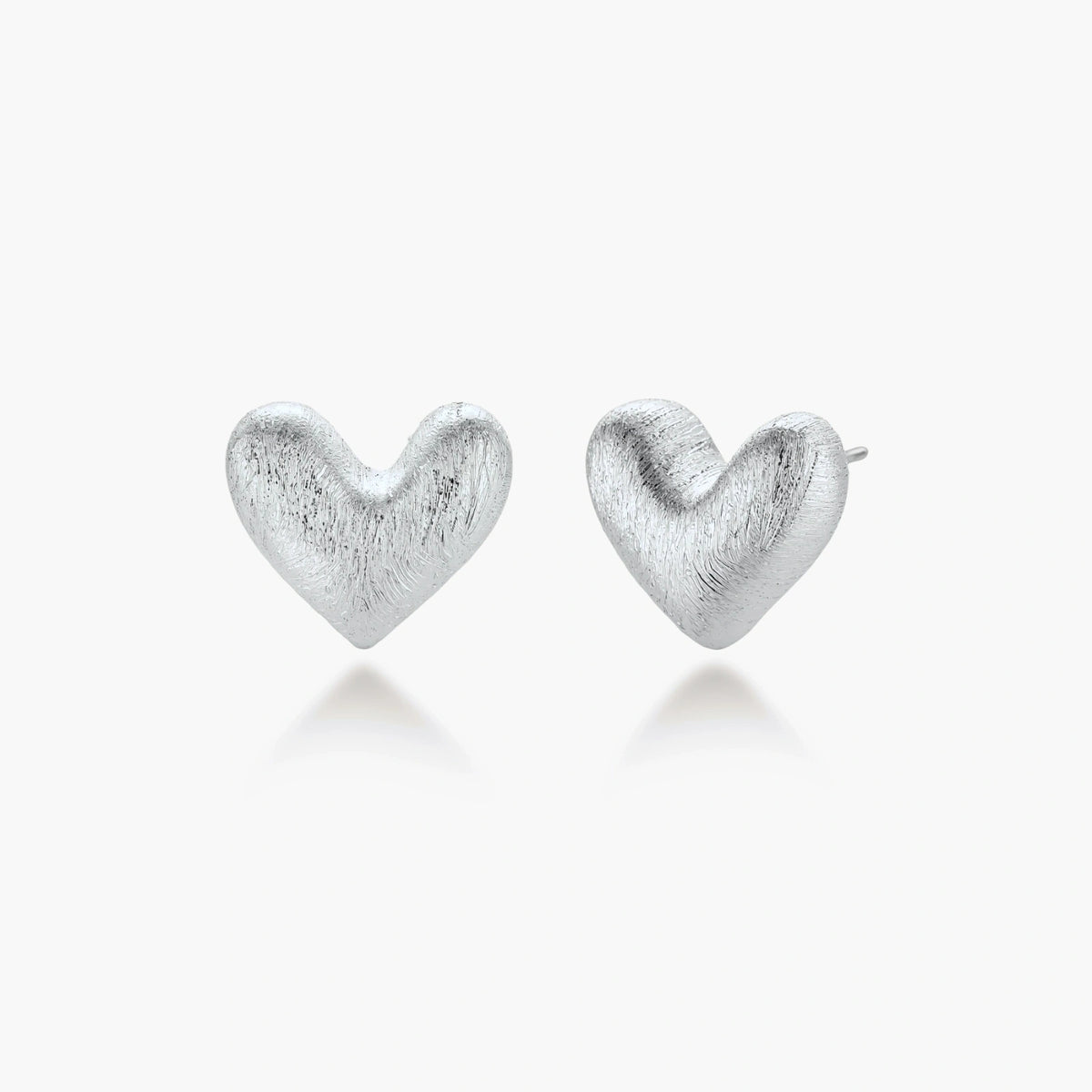 Pair of brushed platinum-plated 925 sterling silver puffy heart stud earrings on a cream background.
