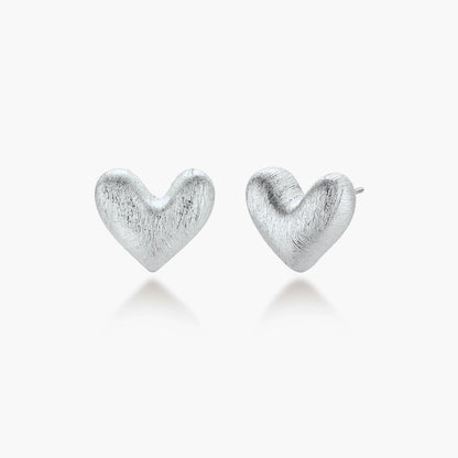 Pair of brushed platinum-plated 925 sterling silver puffy heart stud earrings on a cream background.