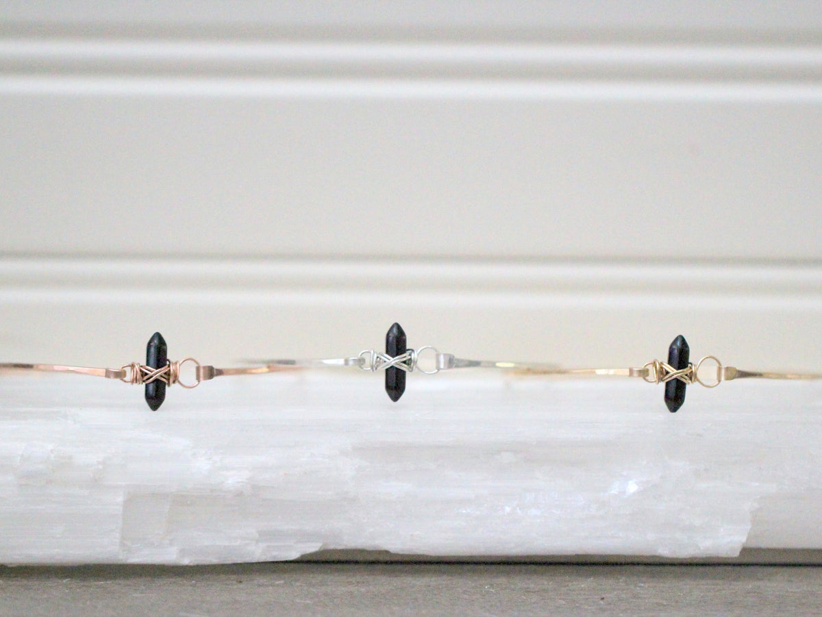 Black obsidian beaded bracelet with engraved crest accent, close-up product view