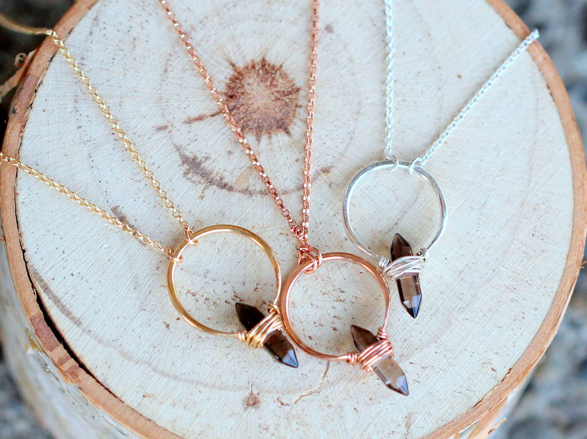 Smoky quartz crest necklace close-up, translucent brown gem and chain links