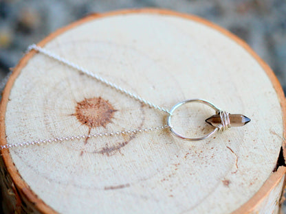 Smoky quartz crest necklace laid flat with silver chain and crest charm