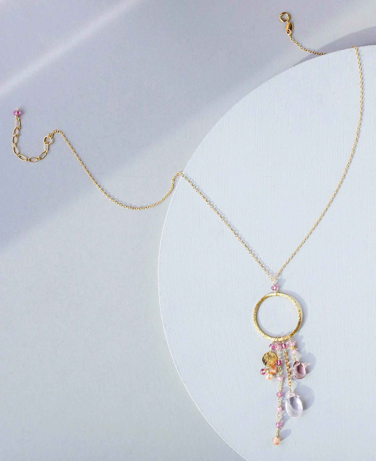 The Ammil Necklace with rose quartz and pink tourmaline gemstones on gold hoop pendant