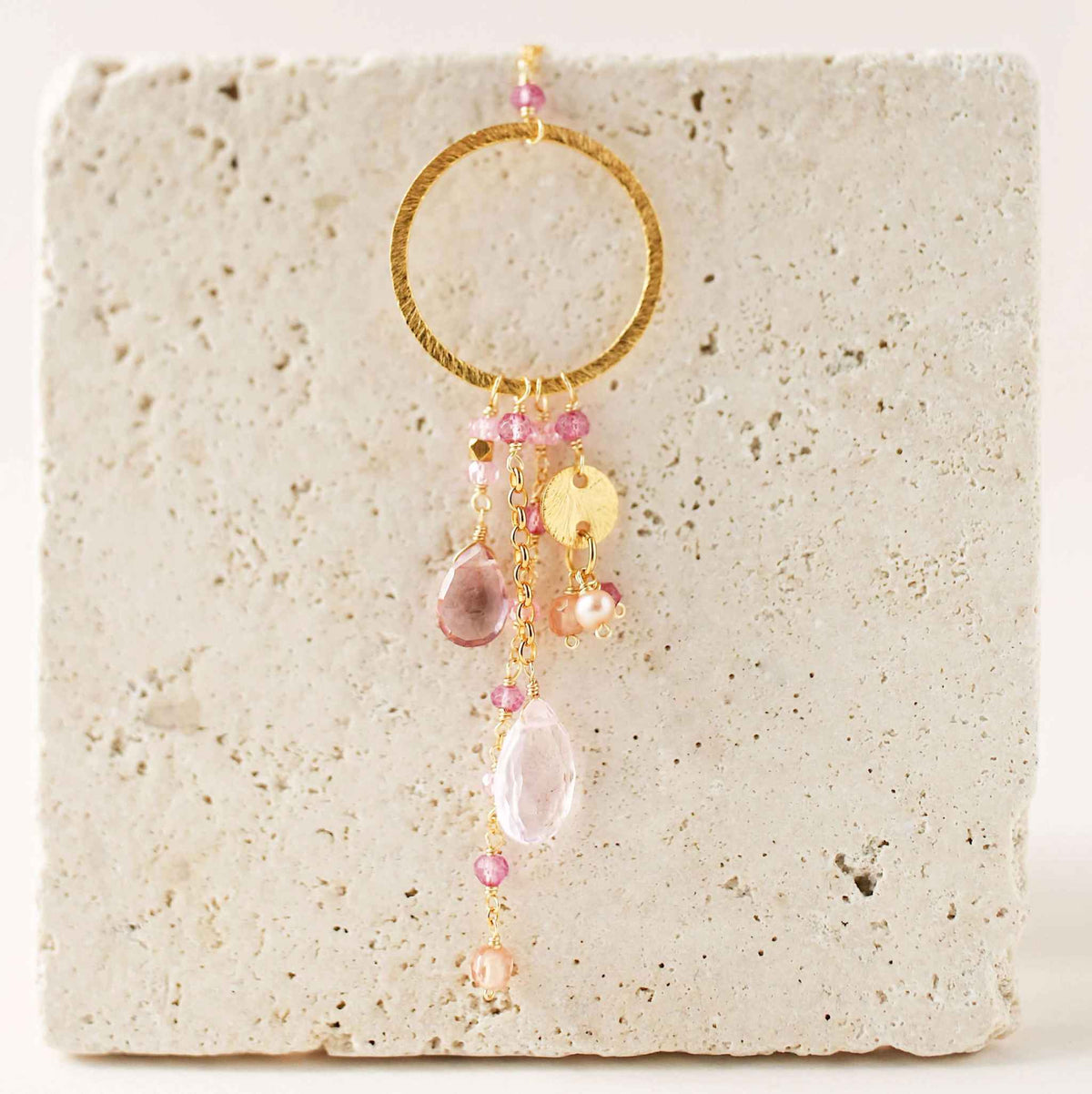 The Ammil Necklace featuring rose pink quartz and tourmaline gemstones with gold hoop and pink gemstone strands