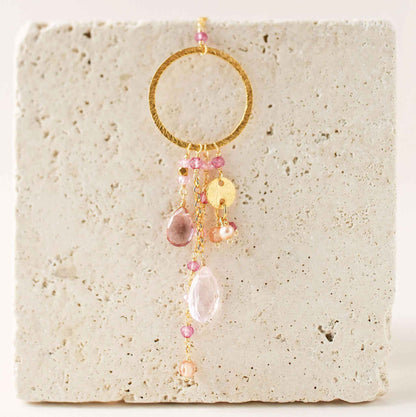The Ammil Necklace featuring rose pink quartz and tourmaline gemstones with gold hoop and pink gemstone strands