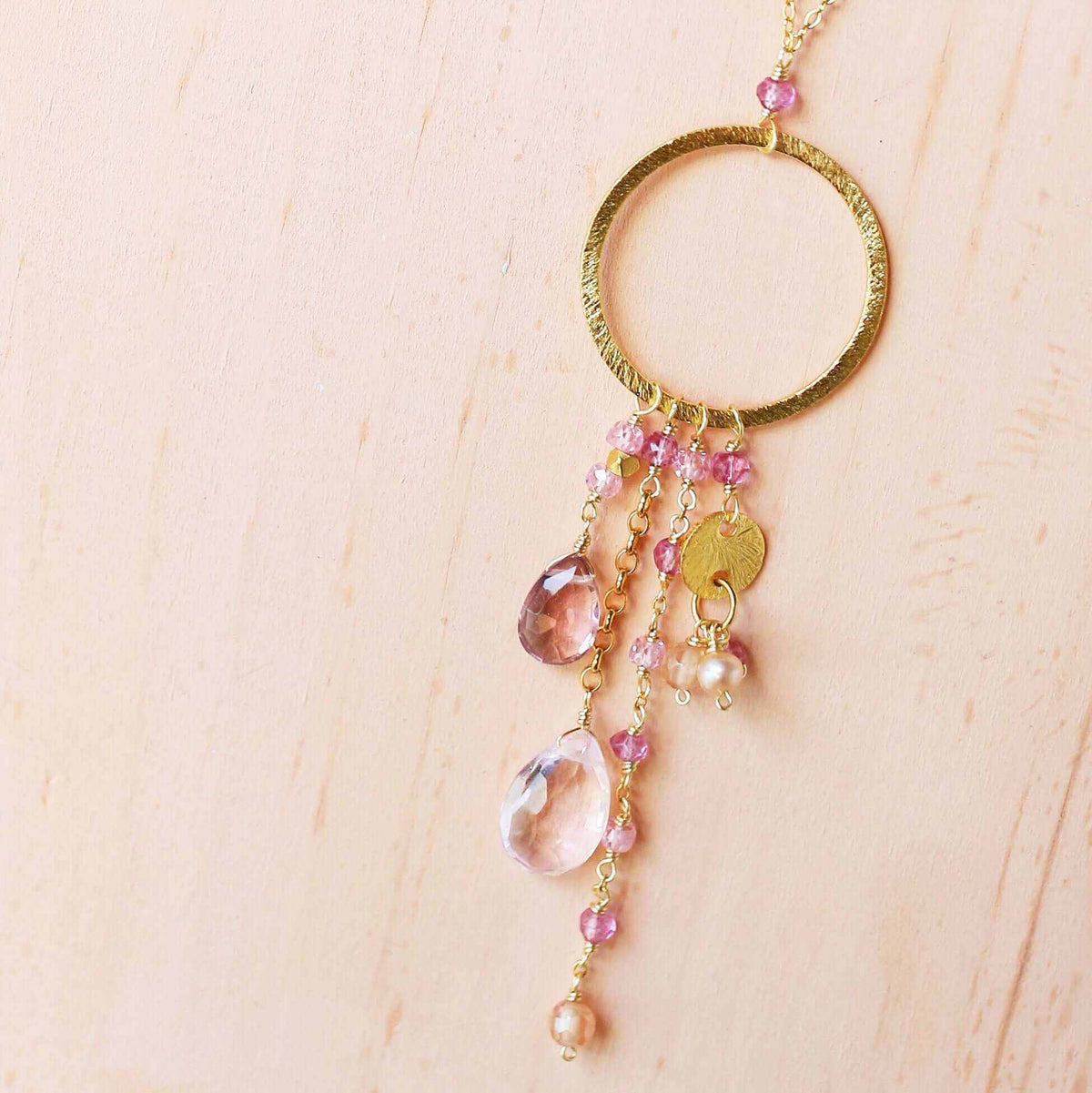 The Ammil Necklace featuring rose pink gemstones with gold hoop and cascading pink gemstone strands